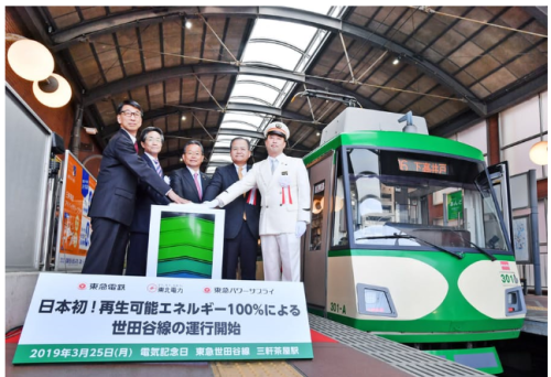 再エネ電力100%路線の運行記念の式典（中央が巴政雄副社長）